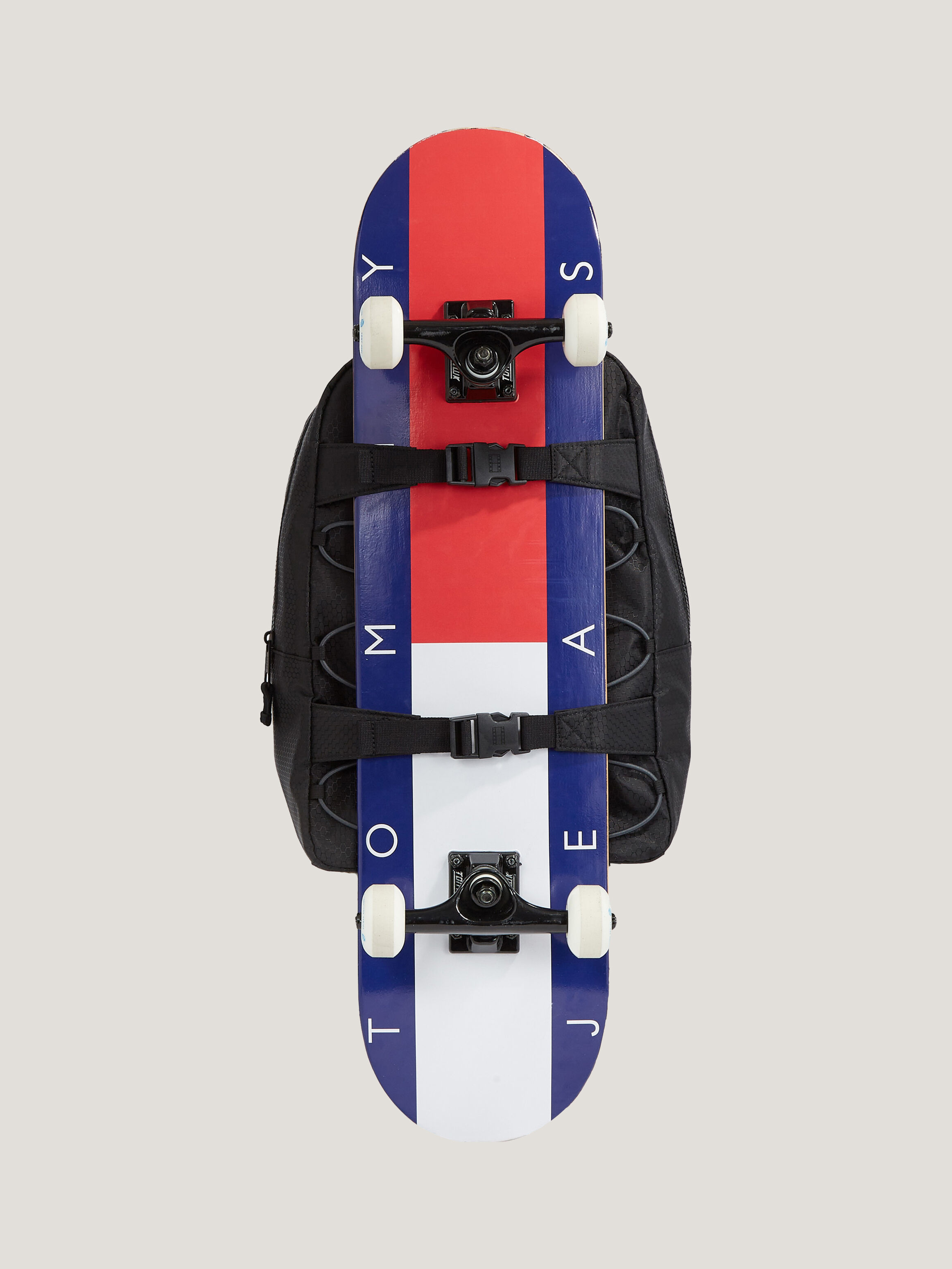 Attach skateboard to top backpack